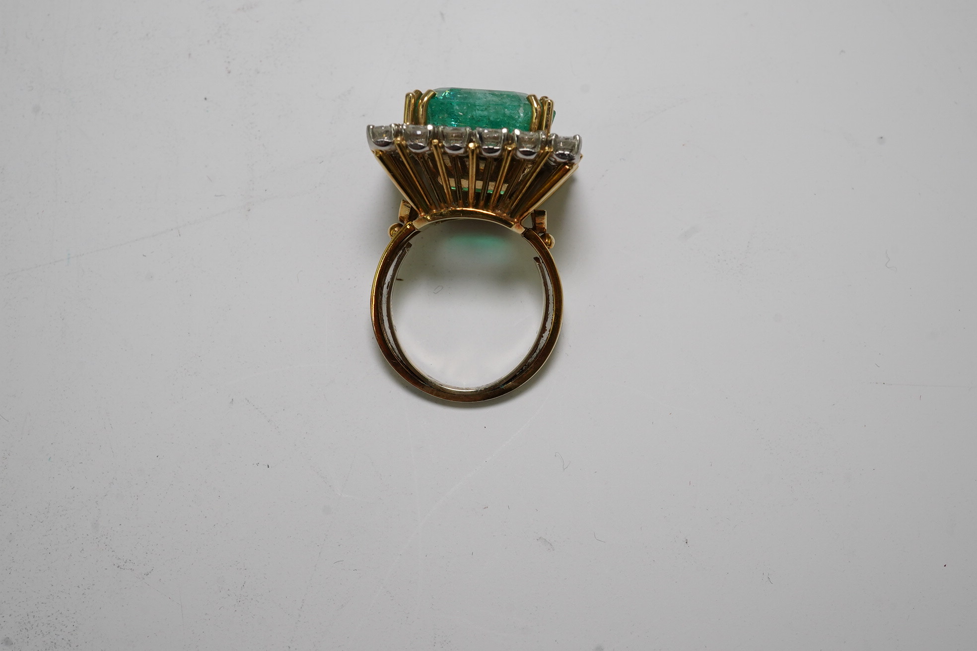 A Stern 18ct white and yellow gold, emerald and diamond dress ring, the central green emerald cut emerald approximately 8.0ct and surrounded by twenty two circular cut diamonds, approximately 2.7ct total